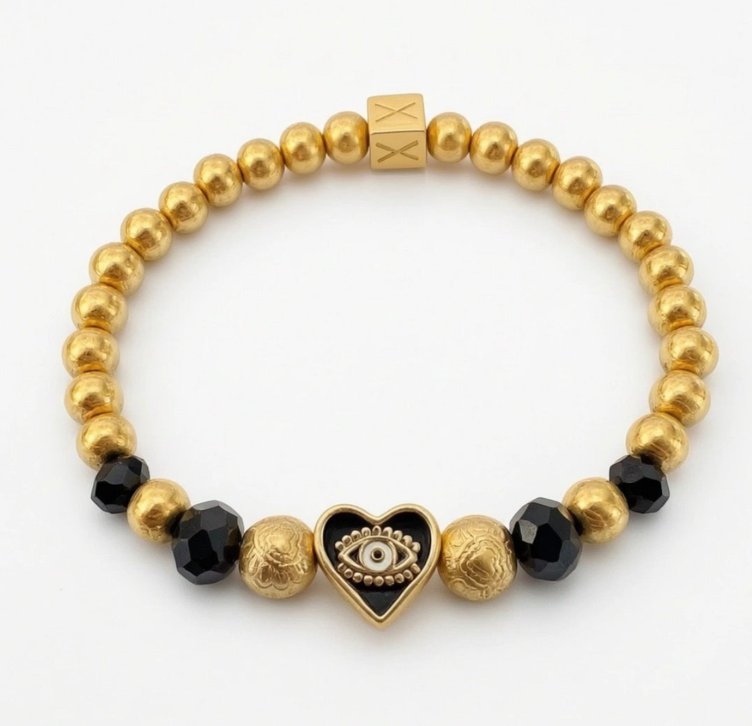 Elegant gold and black beaded bracelet from the Timeless Collection - Aurea Cordis, featuring a heart charm with an eye motif, handcrafted luxury jewelry by atelierX.