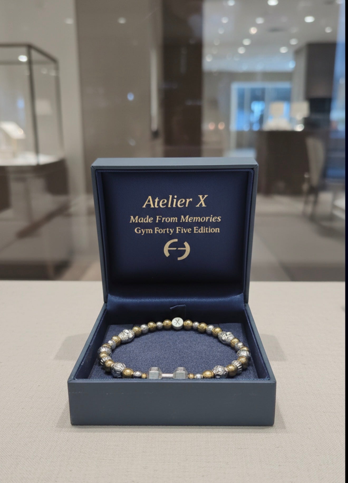 THE X FOR HIM - Live with Strength bracelet displayed in an elegant Atelier X box, featuring gold and silver beads in a luxury handcrafted design.