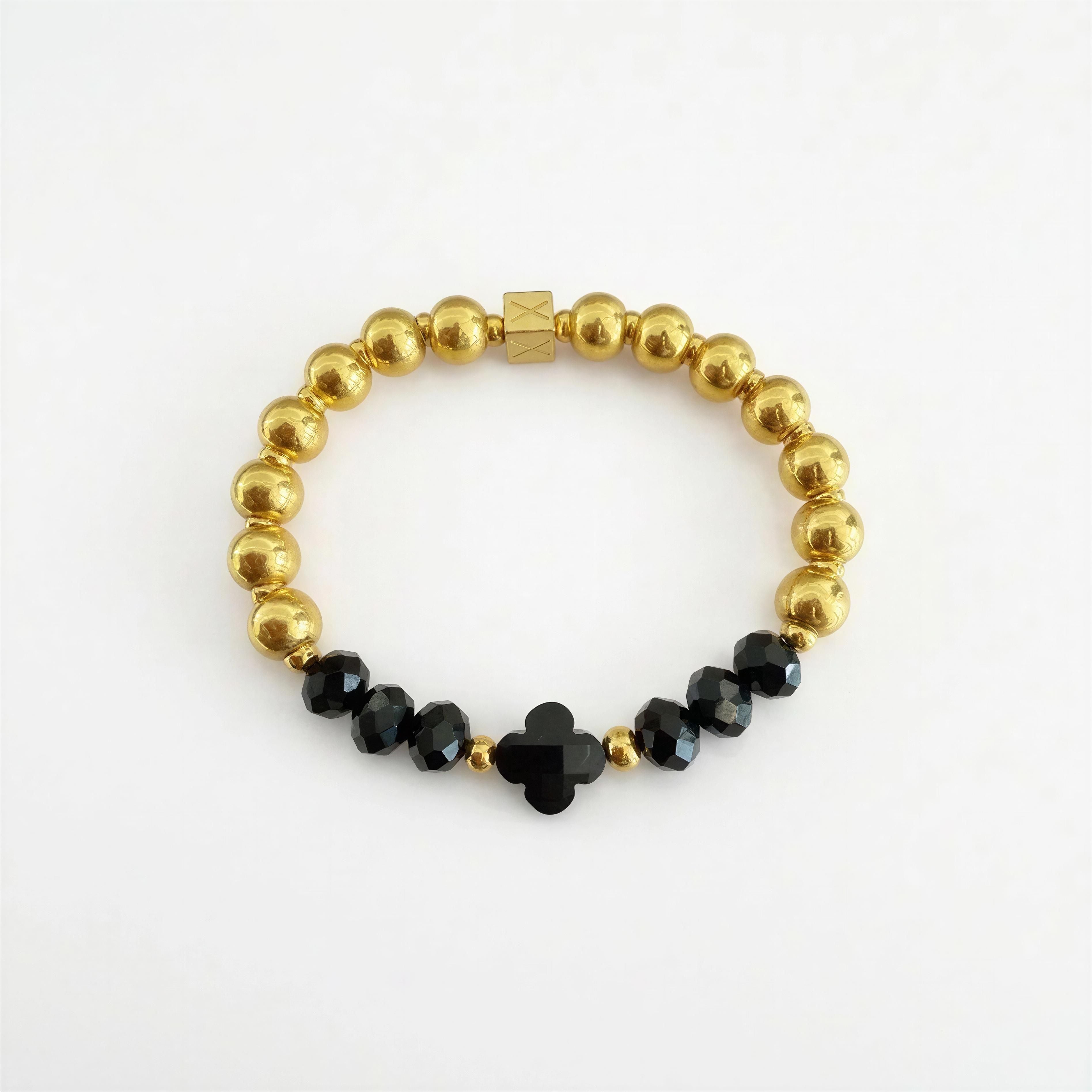 Elegant XX ÉLÉGANCE - Noir Clover bracelet featuring polished gold beads and faceted black beads with a central black clover-shaped charm, handcrafted luxury jewelry.