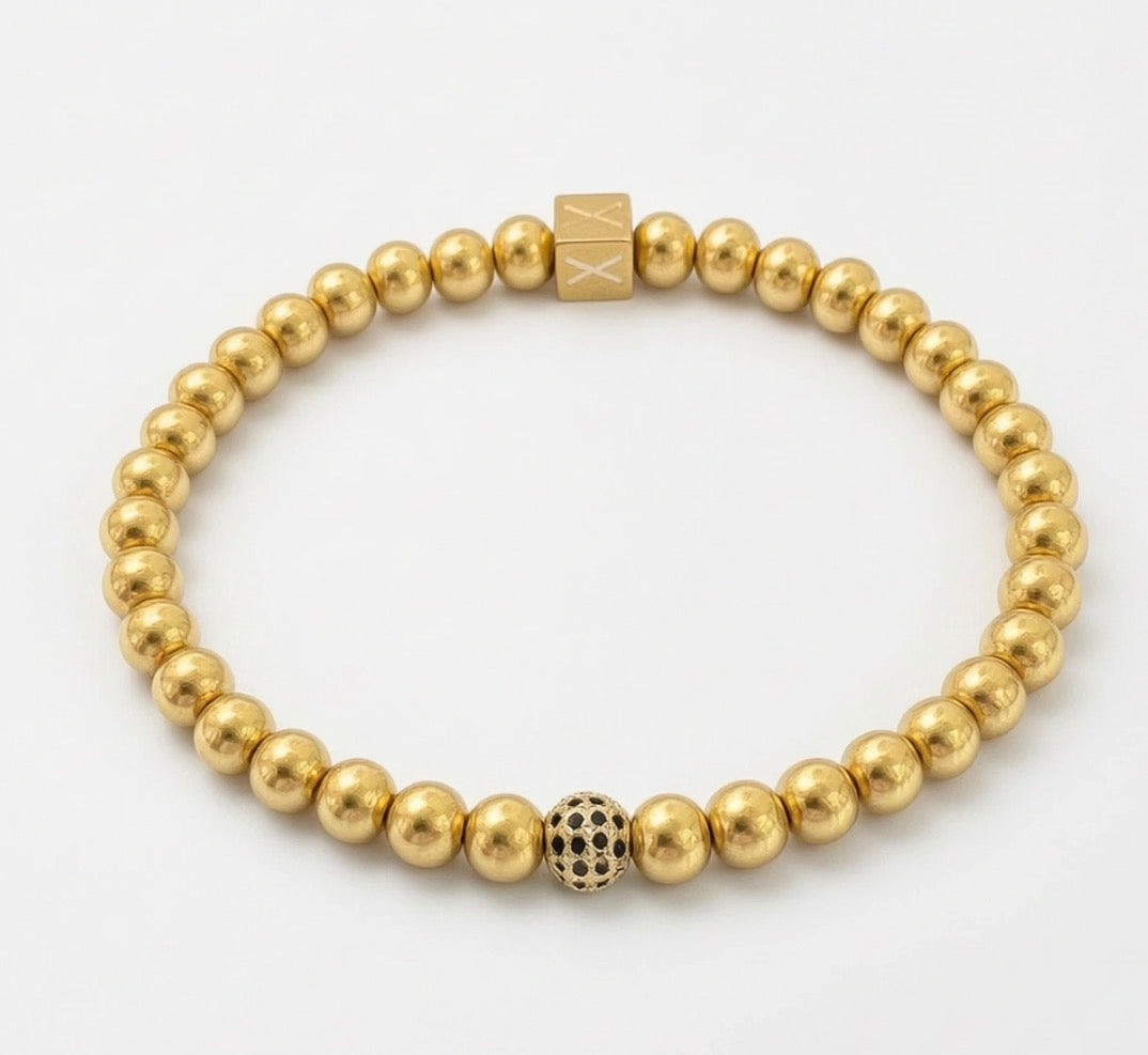 Timeless Collection - Essentia Nox bracelet featuring polished gold beads with a central bead adorned with black accents and a signature gold cube bead, handcrafted luxury jewelry.
