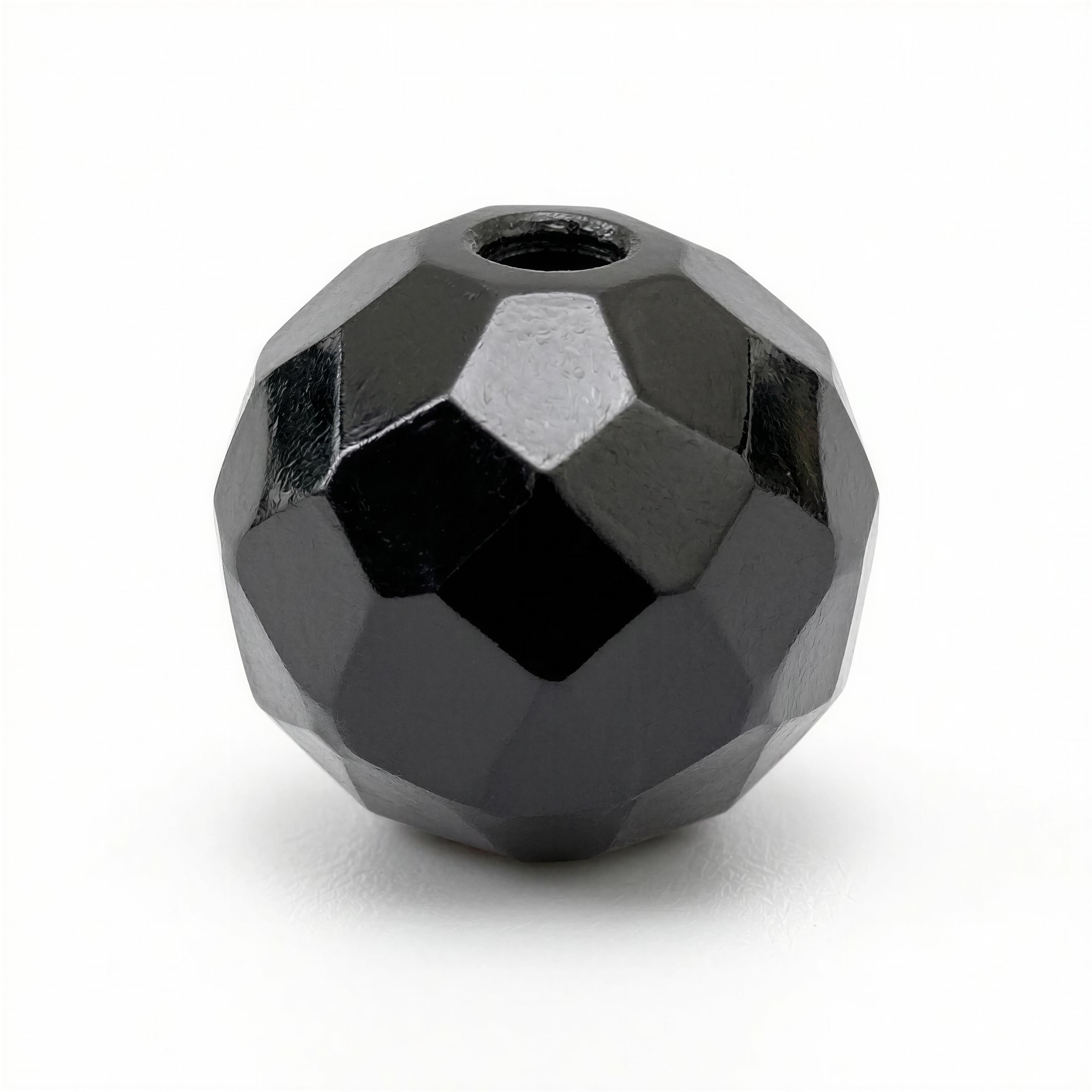 Close-up of a faceted black bead with a glossy finish, featuring geometric facets and a central hole, crafted as part of the Limited Edition - Aurea Memoria Nox collection.