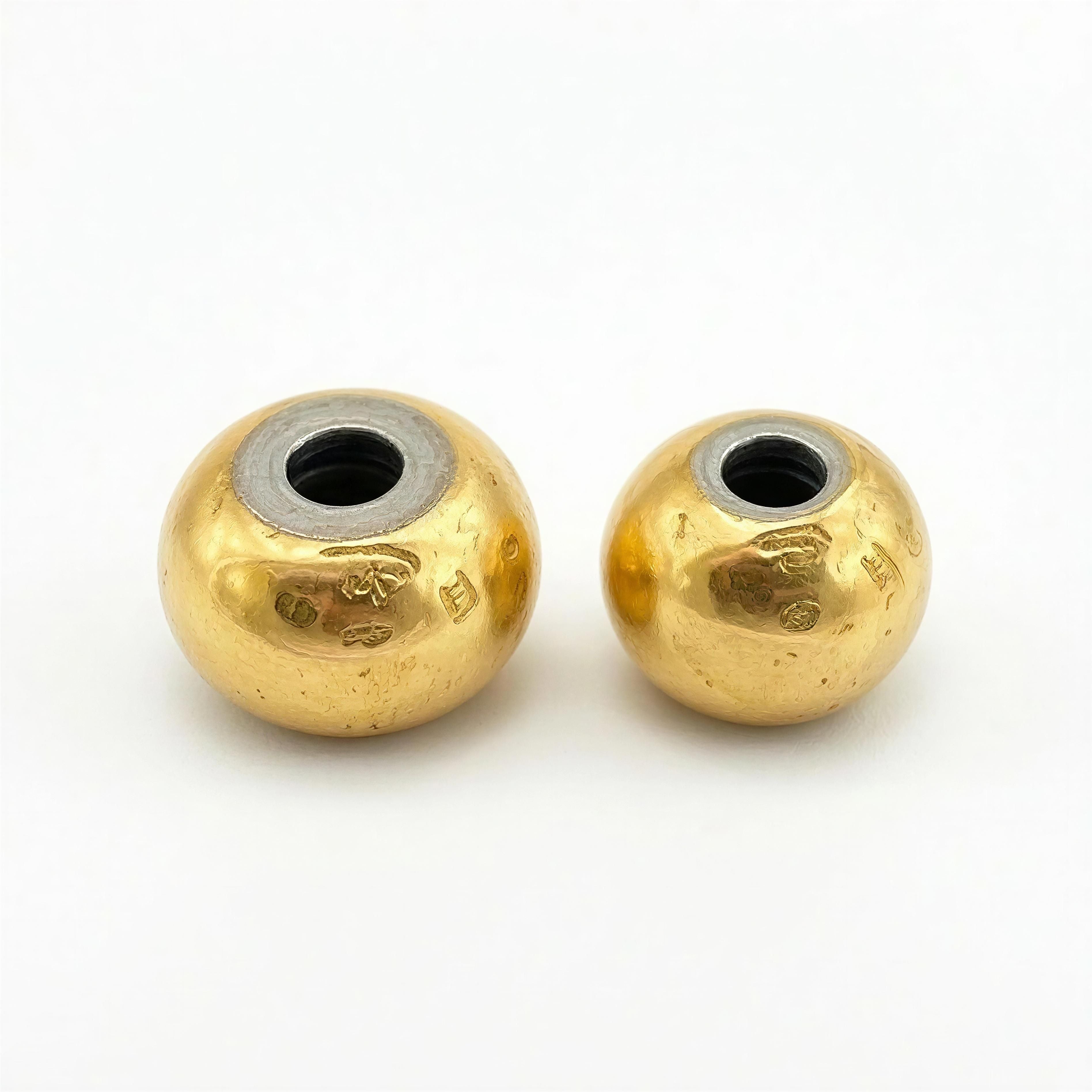 Two polished gold beads with silver-lined holes on a white background, part of THE ESSENTIAL COLLECTION - Pure Balance by Atelier X handcrafted jewelry.