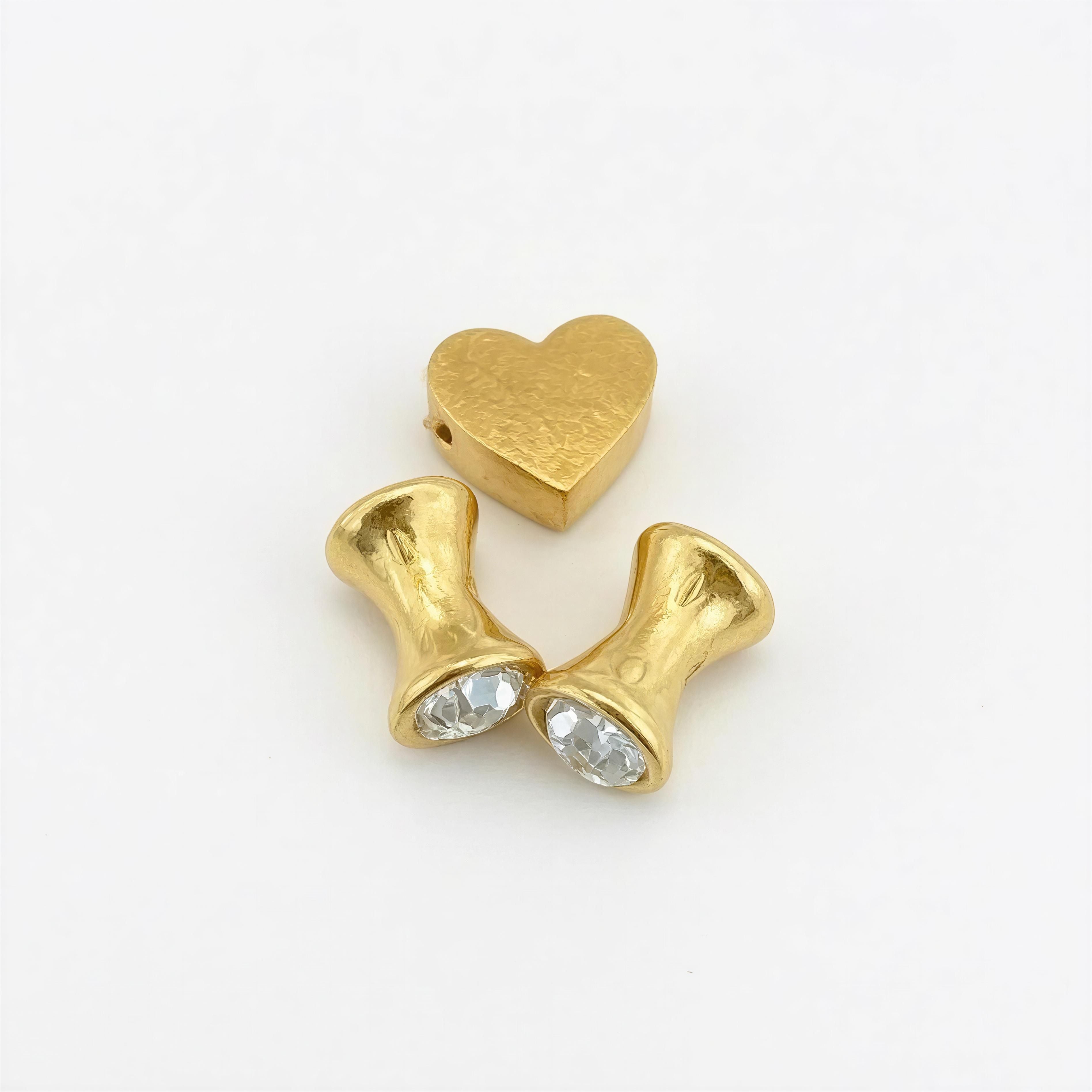 Three gold beads including a heart-shaped bead and two hourglass-shaped beads with clear crystals, designed for the Limited Edition - Aurea Cordis Lux collection.